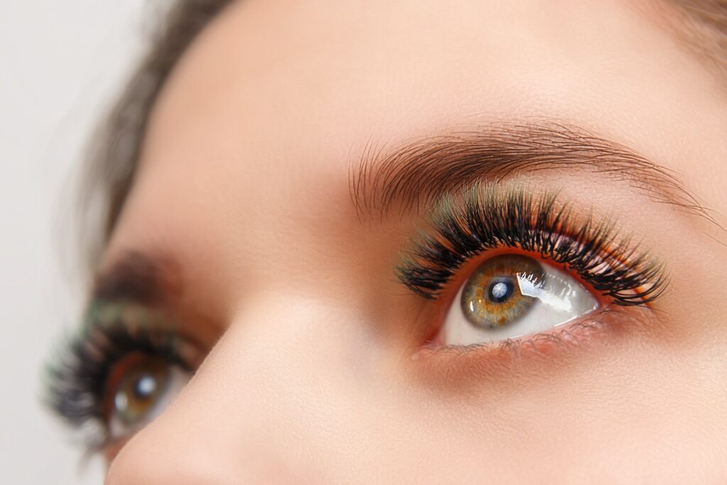 Eyelash Extension Procedure. Woman Eye with Long Eyelashes. Close up, selective focus